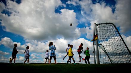 Kinder beim Fußballspielen auf einer Wiese.