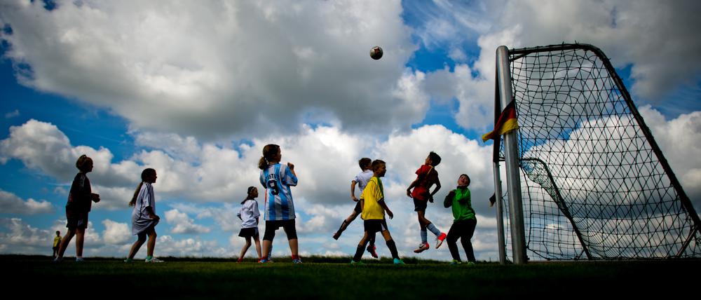 Kinder beim Fußballspielen auf einer Wiese.