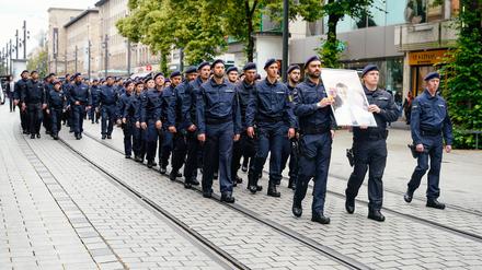 Polizisten tragen ein Bild ihres bei einer Messerattacke tödlich verletzten Kollegen Rouven L. durch die Mannheimer Innenstadt.