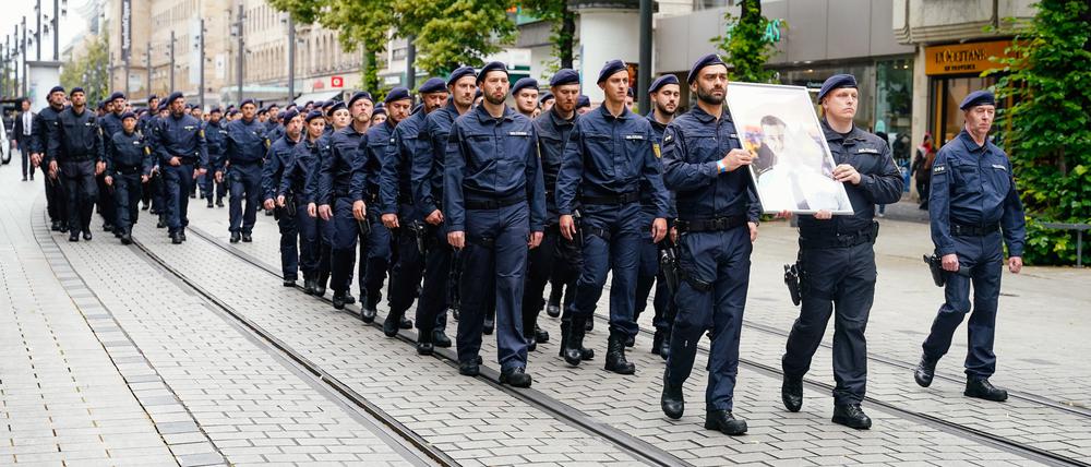Polizisten tragen ein Bild ihres bei einer Messerattacke tödlich verletzten Kollegen Rouven L. durch die Mannheimer Innenstadt.