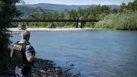 Ein rumänischer Grenzpolizist inspiziert das Ufer des Flusses Theiß: Die Holzbrücke im Hintergrund verbindet Rumänien mit der Ukraine (Symbolbild).