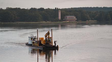 Das Schubboot „Lina“ fährt mit einem Bagger vor der Kulisse der Heilandskirche Sacrow auf der Havel in Richtung Anleger Glienicker Brücke. Wolken und einzelne Schauer erwartet die Menschen in Berlin und Brandenburg.