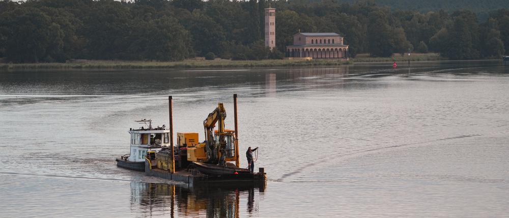 Das Schubboot „Lina“ fährt mit einem Bagger vor der Kulisse der Heilandskirche Sacrow auf der Havel in Richtung Anleger Glienicker Brücke. Wolken und einzelne Schauer erwartet die Menschen in Berlin und Brandenburg.