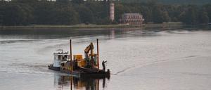 Das Schubboot „Lina“ fährt mit einem Bagger vor der Kulisse der Heilandskirche Sacrow auf der Havel in Richtung Anleger Glienicker Brücke. Wolken und einzelne Schauer erwartet die Menschen in Berlin und Brandenburg.