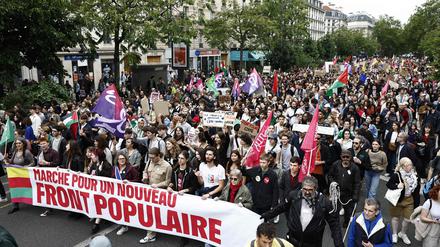 Demonstranten mit einem Spruchband mit der Aufschrift „Marsch für eine neue Volksfront“ nehmen an einer anti-rechtsextremen Kundgebung teil.