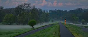 Der Sonnenaufgang scheint auf Wolken über dem Oder-Neiße-Radweg am Deich nahe dem deutsch-polnischen Grenzfluss Oder.