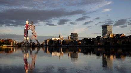 Die Statue ·Molecule Man· des US-Bildhauers Jonathan Borofsky, die anlässlich der Fußball-Europameisterschaft 2024 in Deutschland mit Trikots der deutschen Herren-Nationalmannschaft eingehüllt ist, wird von der Morgensonne angeschienen.