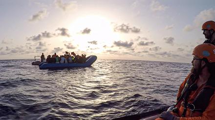 Die von der Seenotrettungsorganisation Sea-Eye herausgegebene Aufnahme zeigt Seenotretter vom Rettungsschiff «Alan Kurdi» die zu einem Schlauchboot voller Flüchtlinge schauen. 