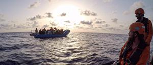 Die von der Seenotrettungsorganisation Sea-Eye herausgegebene Aufnahme zeigt Seenotretter vom Rettungsschiff «Alan Kurdi» die zu einem Schlauchboot voller Flüchtlinge schauen. 