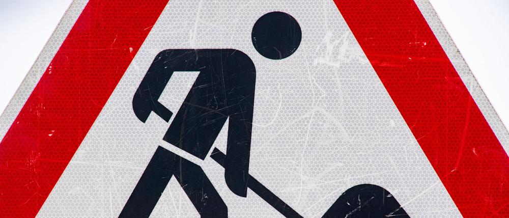 Ein zerkratztes Schild weist auf eine Baustelle hin.
