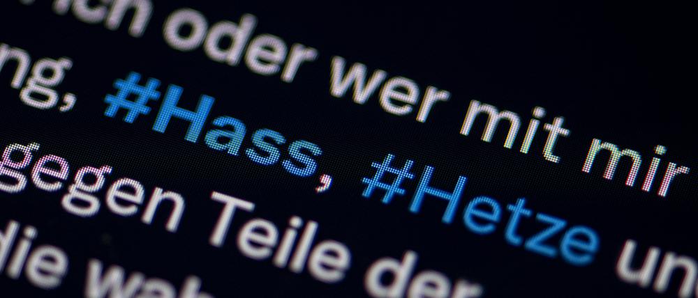 Auf dem Bildschirm eines Smartphones sieht man die Hashtags Hass und Hetze in einem Twitter-Post. 