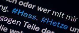 Auf dem Bildschirm eines Smartphones sieht man die Hashtags Hass und Hetze in einem Twitter-Post. 