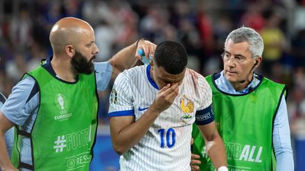 Kylian Mbappé wird nach dem Zusammenstoß mit Österreichs Verteidiger Kevin Danso vom Platz begleitet.