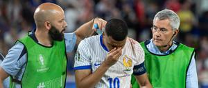 Kylian Mbappé wird nach dem Zusammenstoß mit Österreichs Verteidiger Kevin Danso vom Platz begleitet.
