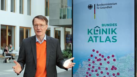 Bundesgesundheitsminister Karl Lauterbach steht neben einem Plakat zum Klinik-Atlas.