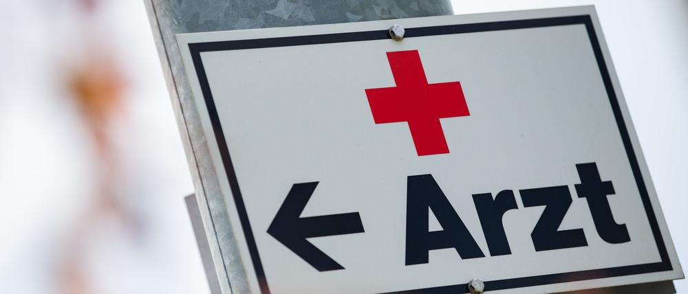 Ein Schild mit der Aufschrift «Arzt» hängt an einer Straßenlaterne.