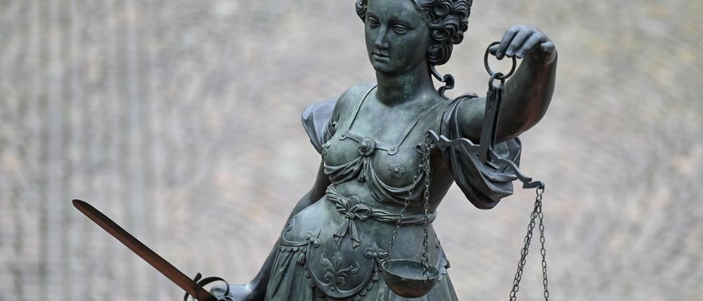 Eine Statue der Justitia hält eine Waage und ein Schwert in der Hand.