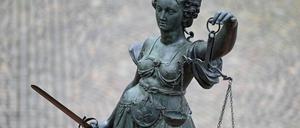 Eine Statue der Justitia hält eine Waage und ein Schwert in der Hand.