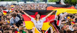 Deutschland-Fans mit Fahnen jubeln beim Public Viewing in der Fanzone am Brandenburger Tor.