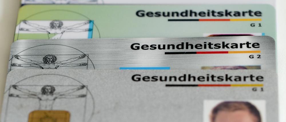 Gesundheitskarten verschiedener Krankenkassen liegen auf einem Tisch.