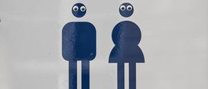Ein Schild Mann und Frau mit einem Pfeil weist im Park Charlottenburg auf die Toiletten hin. Die Piktogramme sind mit Augen beklebt. 