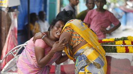 Eine Angehörige eines Mannes, der nach dem Genuss von illegal gebrautem Schnaps im Bezirk Kallakurichi im südindischen Bundesstaat Tamil Nadu gestorben ist, wird neben dem Sarg des Toten von einer Frau getröstet.