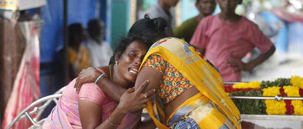 Eine Angehörige eines Mannes, der nach dem Genuss von illegal gebrautem Schnaps im Bezirk Kallakurichi im südindischen Bundesstaat Tamil Nadu gestorben ist, wird neben dem Sarg des Toten von einer Frau getröstet.