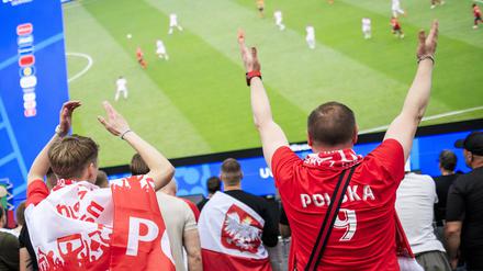 Polnische Fans stehen vor der Großleinwand in der Fanzone am Brandenburger Tor und sehen sich das Spiel Polens gegen Österreich an.