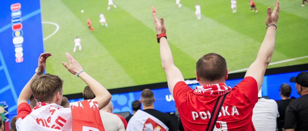 Polnische Fans stehen vor der Großleinwand in der Fanzone am Brandenburger Tor und sehen sich das Spiel Polens gegen Österreich an.