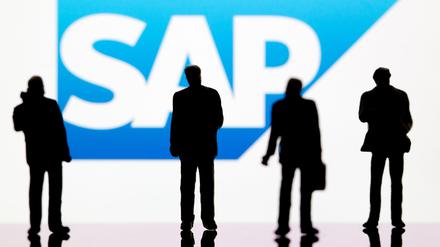 Kleine Plastikfiguren vor dem Logo des DAX-Unternehmens SAP. In Deutschland streicht der Konzern zahlreiche Stellen.