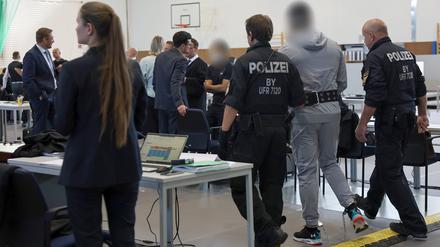 Ein Angeklagter winkt beim Neubeginn eines Prozesses wegen Geldautomaten-Sprengungen in ganz Deutschland iBekannten auf der Besuchertribüne zu. Die 16 Angeklagten sollen zwischen 2021 und 2023 in 30 Fällen Geldautomaten im ganzen Bundesgebiet gesprengt haben, um an Bargeld zu kommen. Ihre Beute betrug laut Anklage mehr als drei Millionen Euro - der entstandene Schaden mehr als fünfeinhalb Millionen.