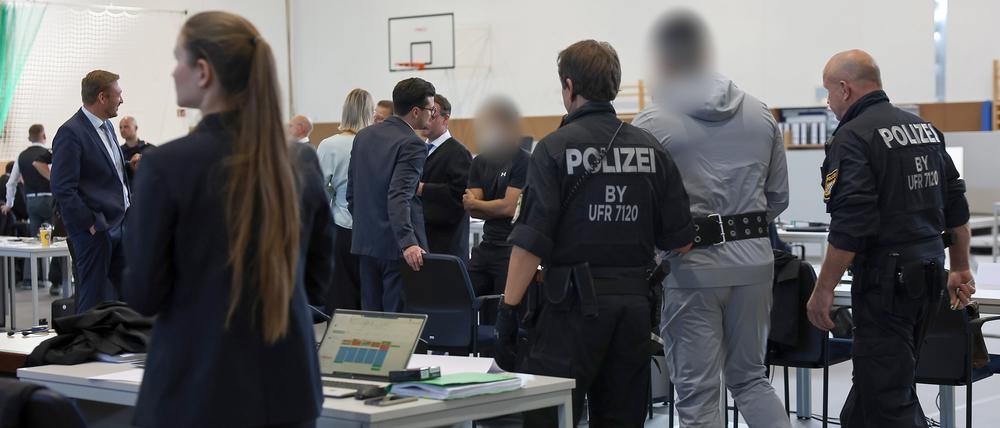 Ein Angeklagter winkt beim Neubeginn eines Prozesses wegen Geldautomaten-Sprengungen in ganz Deutschland iBekannten auf der Besuchertribüne zu. Die 16 Angeklagten sollen zwischen 2021 und 2023 in 30 Fällen Geldautomaten im ganzen Bundesgebiet gesprengt haben, um an Bargeld zu kommen. Ihre Beute betrug laut Anklage mehr als drei Millionen Euro - der entstandene Schaden mehr als fünfeinhalb Millionen.