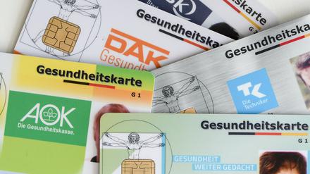 Gesundheitskarten verschiedener Krankenkassen liegen auf einem Tisch.