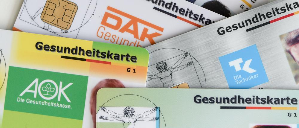 Gesundheitskarten verschiedener Krankenkassen liegen auf einem Tisch.