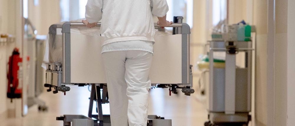 Eine Krankenpflegerin schiebt ein Krankenbett durch einen Krankenhausflur. (Symbolbild)