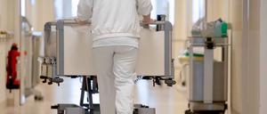 Eine Krankenpflegerin schiebt ein Krankenbett durch einen Krankenhausflur.