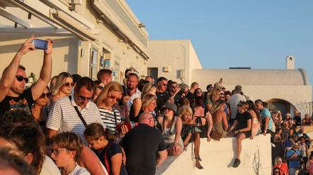 Viele Touristen beobachten dicht gedrängt den Sonnenuntergang auf der Insel Santorini.