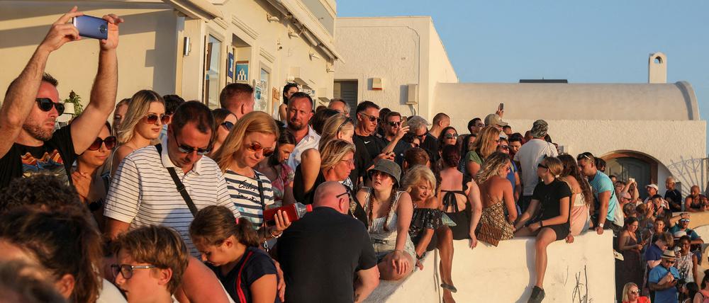Viele Touristen beobachten dicht gedrängt den Sonnenuntergang auf der Insel Santorini.