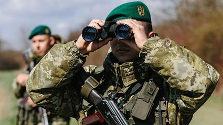 Ein Soldat der Grenzschutzeinheit Kosyno sucht mit einem Fernglas die Umgebung ab. 