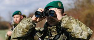 Ein Soldat der Grenzschutzeinheit Kosyno sucht mit einem Fernglas die Umgebung ab. 