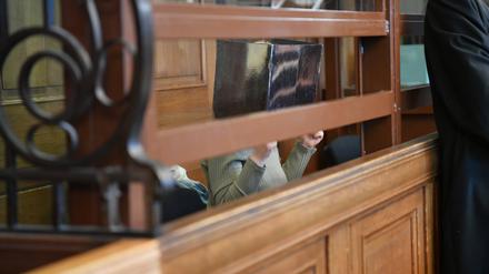 Eine Frau sitzt im Kriminalgericht Moabit auf einer Bank in einem Gerichtssaal. Der 42-jährigen Frau wird Totschlag sowie Tötung auf Verlangen vorgeworfen, einem ebenfalls angeklagten 71-jährigen Mann Totschlag durch Unterlassen. Die Frau soll am 13. Oktober 2023 in Berlin-Köpenick zunächst ihre Tochter umgebracht haben. Dann soll sie ihre 68 Jahre alte Mutter auf deren ausdrückliches Verlangen getötet haben. 