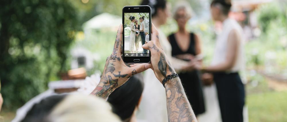 Eine Frau macht mit dem Handy ein Foto von einem Brautkleid. Auf Pinterest suchen viele Bräute nach Ideen mit Bildern wie dem, das die Frau dort macht.