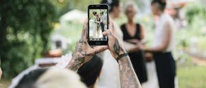 Eine Frau macht mit dem Handy ein Foto von einem Brautkleid. Auf Pinterest suchen viele Bräute nach Ideen mit Bildern wie dem, das die Frau dort macht.