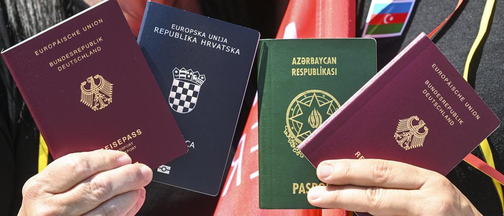 Menschen zeigen bei einem Fototermin zur Unterstützung des neuen Staatsangehörigkeitsrecht zwei Pässe: den deutschen und den kroatischen (links) sowie den deutschen und aserbaidschanischen.