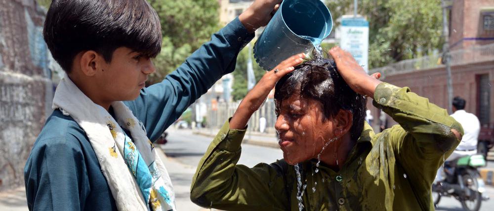 Ein Kind schüttet einer anderen Person Wasser über den Kopf.