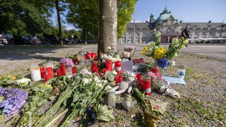 Blumen, Kerzen und handgeschriebene Trauerbekundungen stehen an einem Baum im Kurpark Bad Oeynhausen.