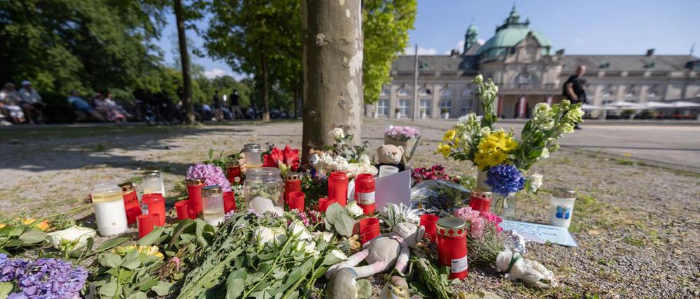 Blumen, Kerzen und handgeschriebene Trauerbekundungen stehen an einem Baum im Kurpark Bad Oeynhausen.