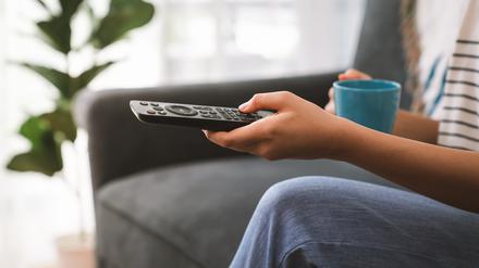 Eine Hand bedient eine Fernbedienung für ein TV-Gerät (Symbolbild).