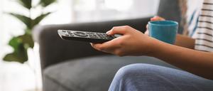 Eine Hand bedient eine Fernbedienung für ein TV-Gerät (Symbolbild).