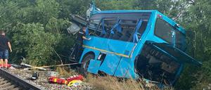 Slowakei, Nové Zámky: Ein verunglückter Bus liegt an der Unfallstelle neben den Eisenbahnschienen. Bei einem Unfall zwischen einem Zug und einem Bus sind am 27.06.2024 mehrere Menschen gestorben und weitere verletzt worden.